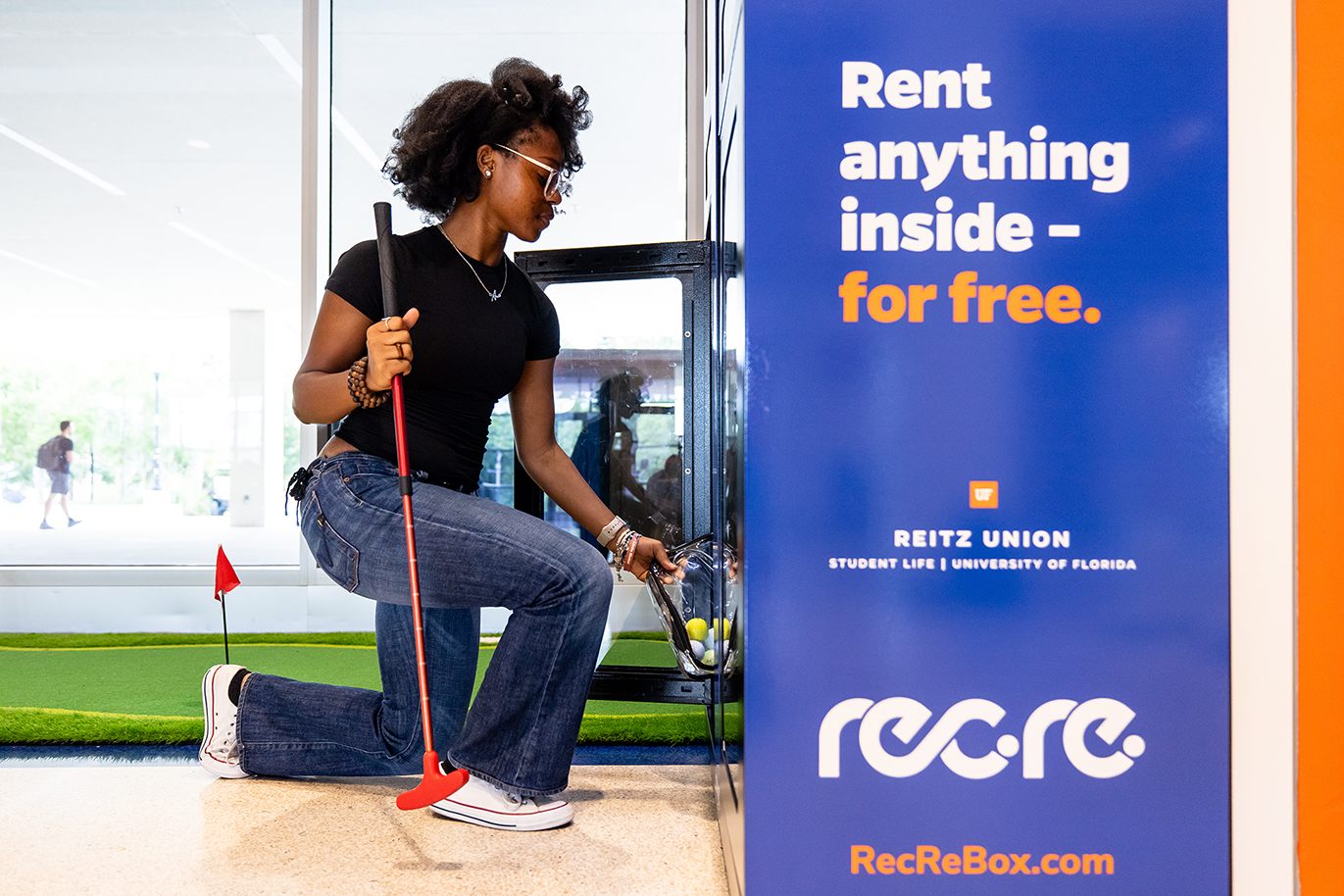A student retrieving putting equipment from the RecRe Box at the Reitz Union.