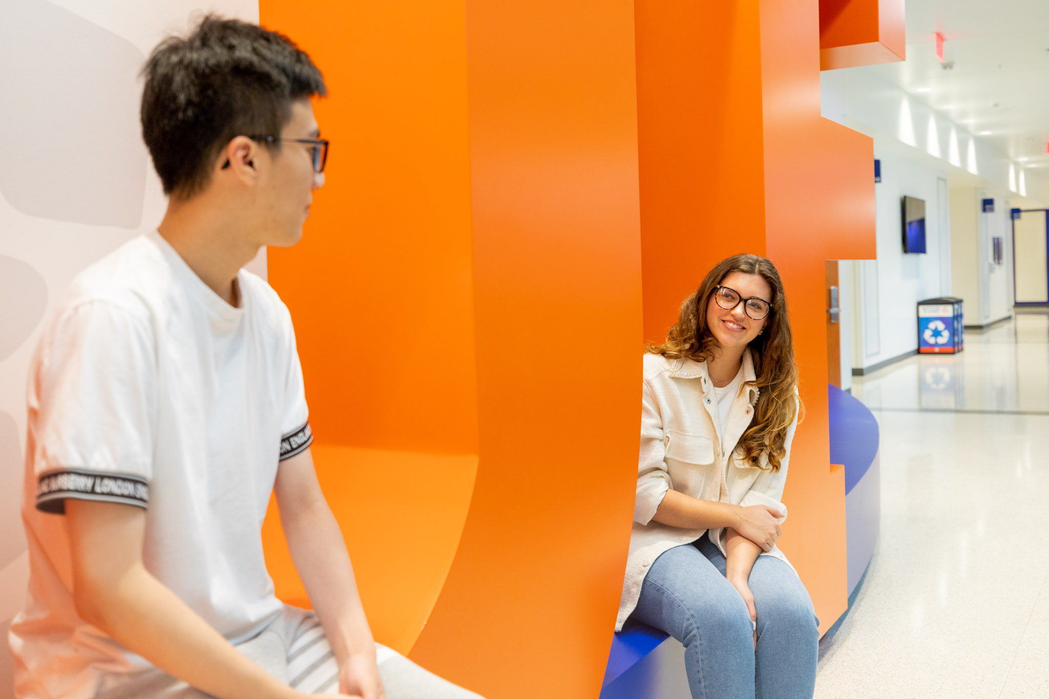 Students sitting on the UF letters in the Reitz Union Atrium having a conversation.