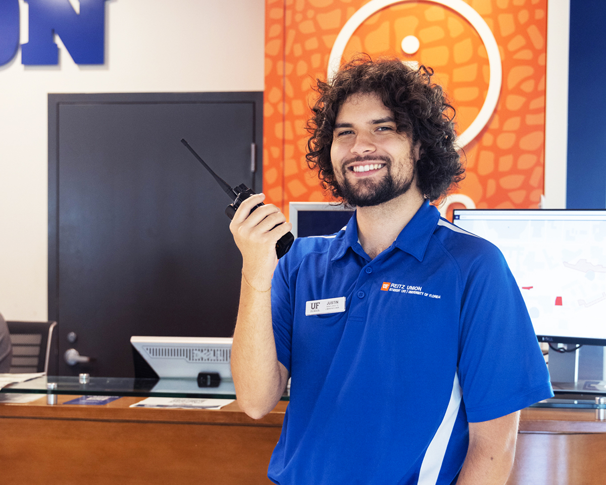 An Info Desk employee holding a walkie-talkie in front of the information desk at the Reitz Union.